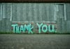 Turkoosi graffiti, jossa lukee Thank you, harmaalla betoniseinällä.