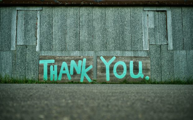 Turkoosi graffiti, jossa lukee Thank you, harmaalla betoniseinällä.