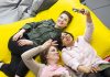 Kolme opiskelijaa makoilee säkkituoleilla. Yksi ottaa ryhmästä selfien.