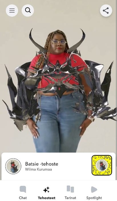 Kuvakaappaus Wilma Kurumaan Snapchatista, jossa naisen päällä on lisätyn todellisuuden mahdollistama metallinhohtoinen monimuotoinen asuste.