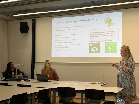 Kolme henkilöä pitää esitelmää luokkatilassa