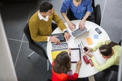 Four individuals seated around a round table, picture taken from bird-eye view