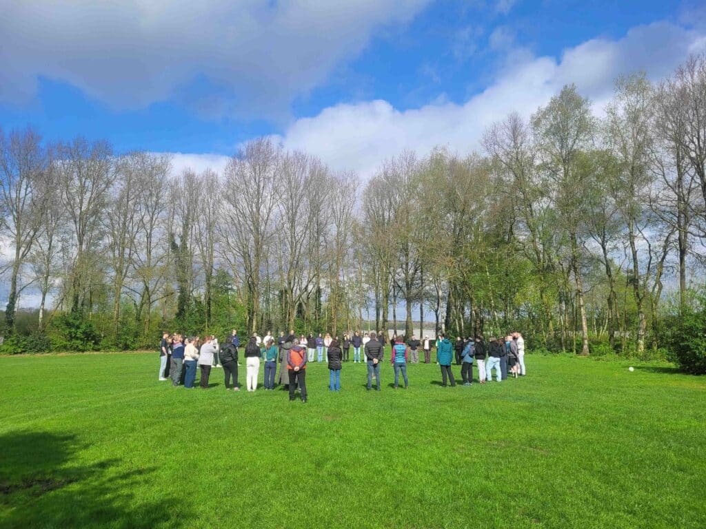 Henkilöt seisovat isossa ringissä ulkona.
