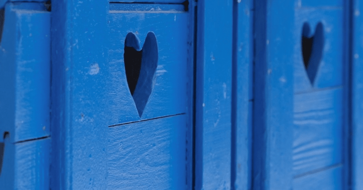 Sinisiin puuoviin leikattu sydämenmuotoinen aukko