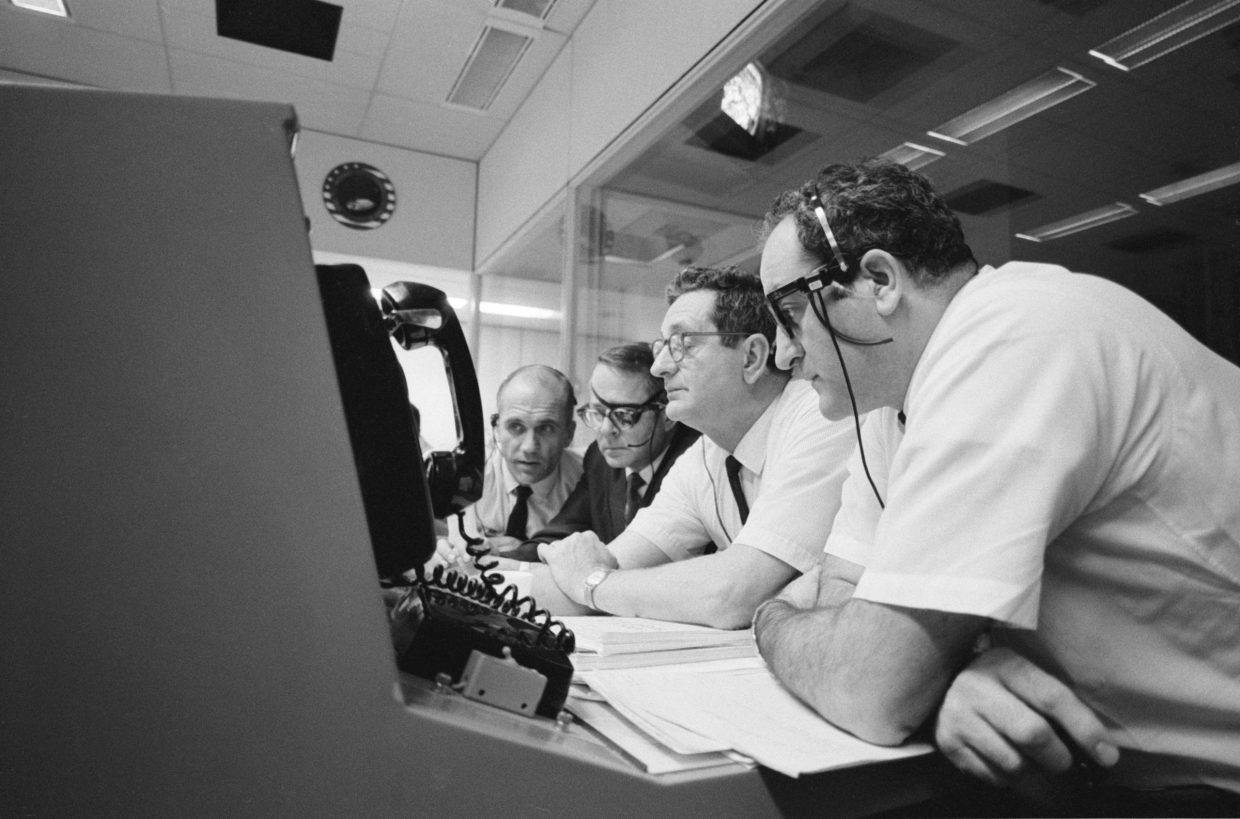 Apollo 13 lento, NASA, neljä miestä istuu rivissä ja tarkkailee monitoria,16 huhtikuuta 1970, etualalla lankapuhelin, mustavalkoinen.