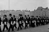 Mustavalkoinen kuva vuodelta 1957, hattupäisiä tohtoreita kävelemässä Senaatintorilla jonossa.