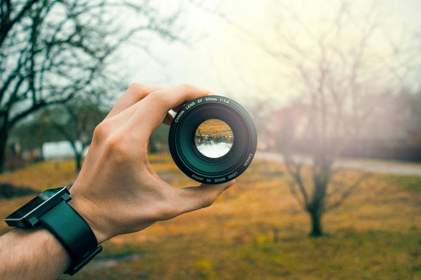 A hand holding a lense over a landscape.