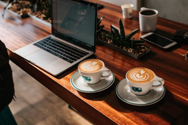 Kaksi kahvikuppia sekä kannettava tietokone