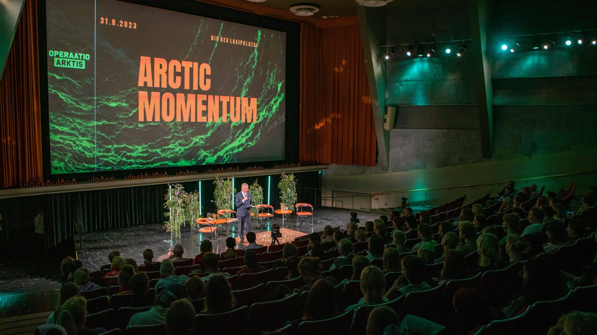 Kuvassa näkyy lähes täysi Amos Rexin auditoriosali. Pekka Haavisto puhuu tilaisuuteen saapuneille vieraille.