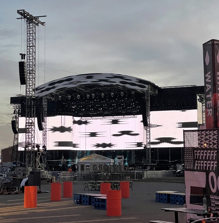 http://Flow%20Festivaalin%20päälava,%20jossa%20suuri%20LED-näyttö%20peittää%20lavan%20etuosan%20ja%20yläosan.%20Näytöllä%20näkyy%20mustavalkoisia%20graafisia%20kuvioita.%20Lavan%20ympärillä%20on%20metallitukirakenteita,%20ja%20etualalla%20näkyy%20punaisia%20tynnyreitä,%20sinisiä%20muovilaatikoita%20sekä%20pöytiä%20ja%20tuoleja%20odottamassa%20yleisön%20saapumista.