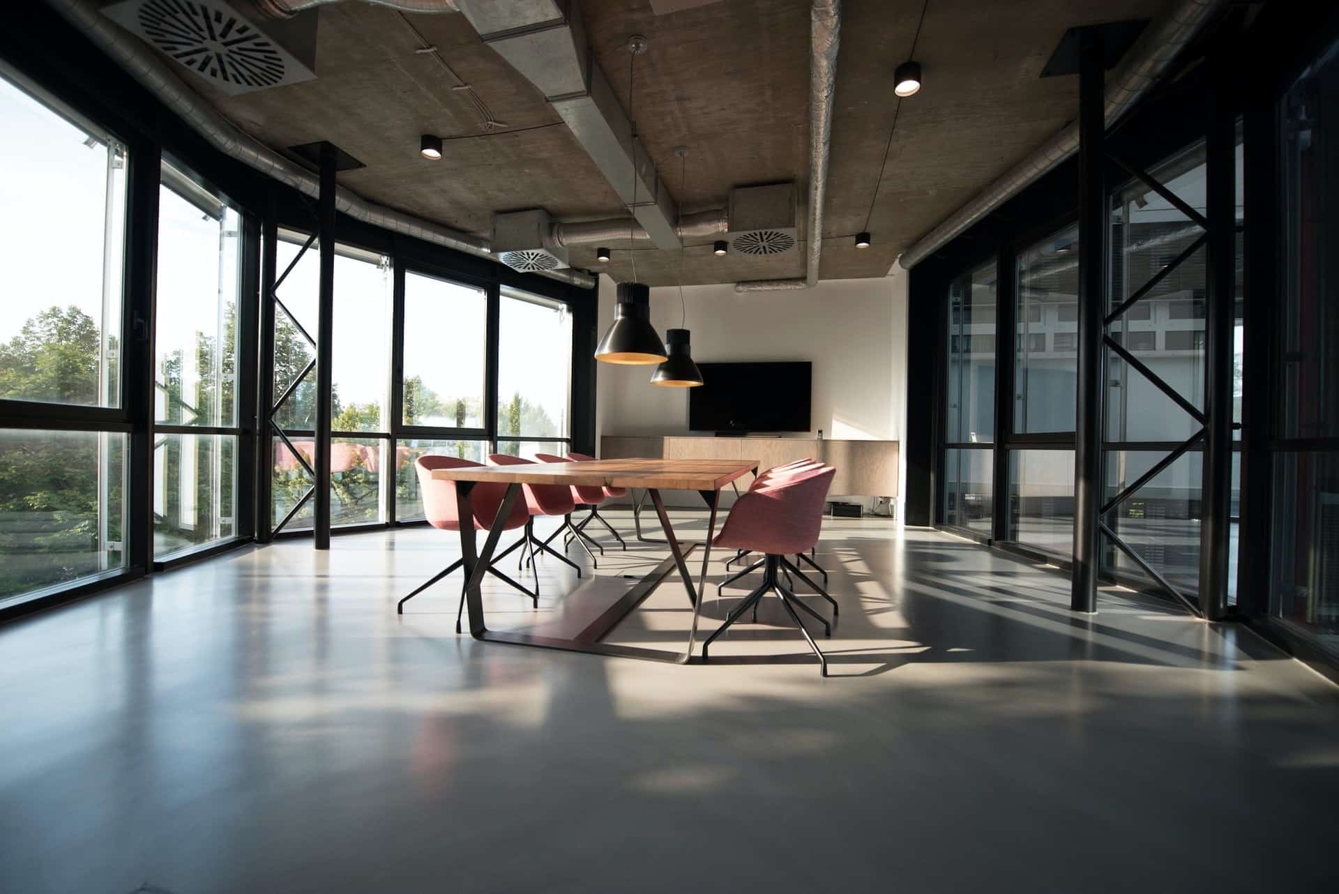 An empty office room, with long table in middle, big glass windeows on one wall
