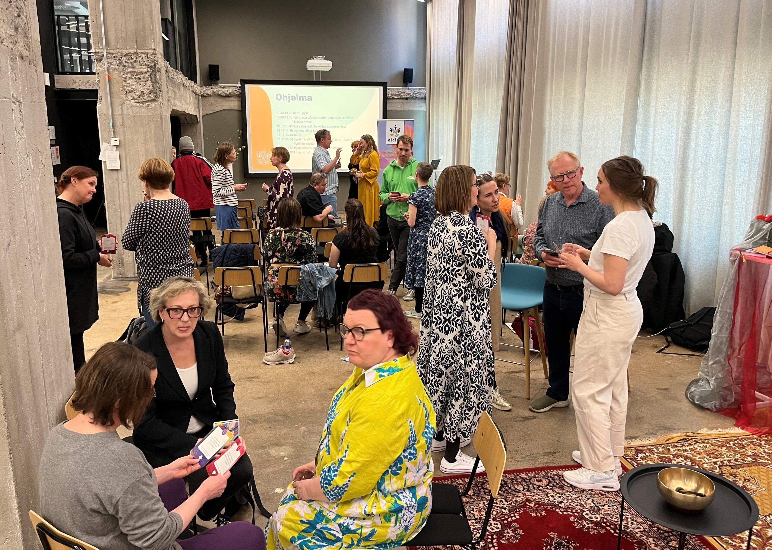 Eloisa-hankkeen lopputapahtumassa Luovuuden jyviä, työhyvinvoinnin kasvua käydään tutustumiskeskustelua. Etualalla alustajana toiminut emerita professori Pirjo Ståhle ja Metropolian kulttuuripalveluiden ja musiikin lehtori Raili Honkanen-Korhonen.